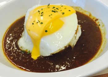 Poached egg on a rich beef curry rice dish.