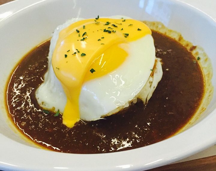 Poached egg on a rich beef curry rice dish.