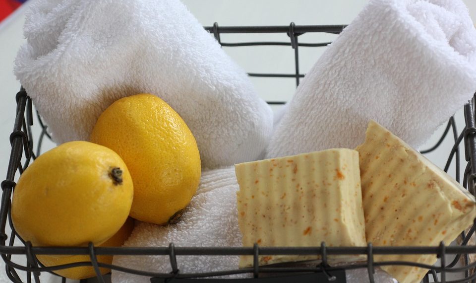Basket with lemons, rolled towels, and natural soap bars.