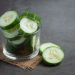 Sliced cucumber slices in a glass bowl on a burlap mat.