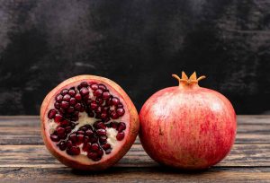 Whole and half pomegranate on wooden table.