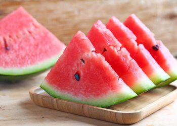 Sliced watermelon on a wooden tray.