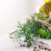 Fresh rosemary and oregano with peppercorns on a rustic table.