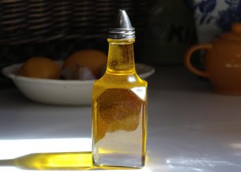 Bottle of olive oil with sunlight reflecting on a kitchen countertop.