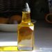 Bottle of olive oil with sunlight reflecting on a kitchen countertop.