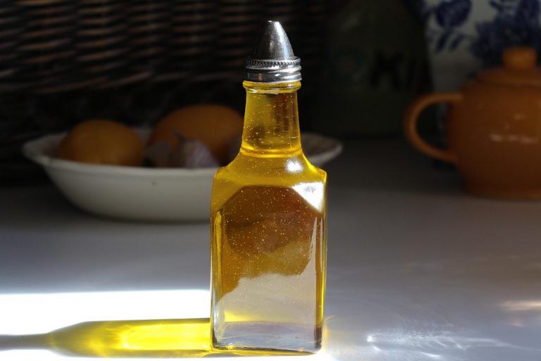 Bottle of olive oil with sunlight reflecting on a kitchen countertop.
