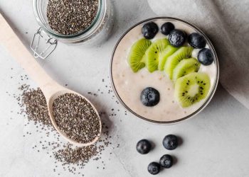 Chia pudding topped with kiwi and blueberries surrounded by seeds.