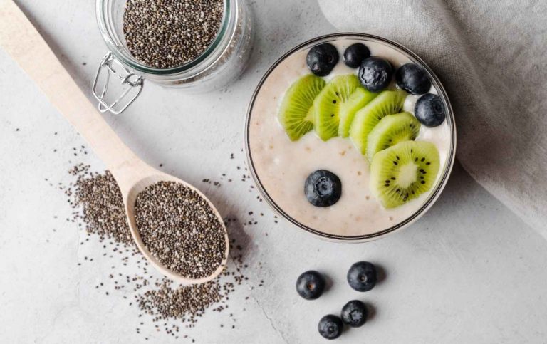 Chia pudding topped with kiwi and blueberries surrounded by seeds.