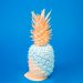 Unique pastel-painted pineapple against a blue background.