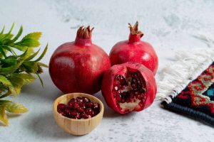 Pomegranates and seeds in a bowl on a table with a decorative cloth.