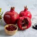 Pomegranates and seeds in a bowl on a table with a decorative cloth.