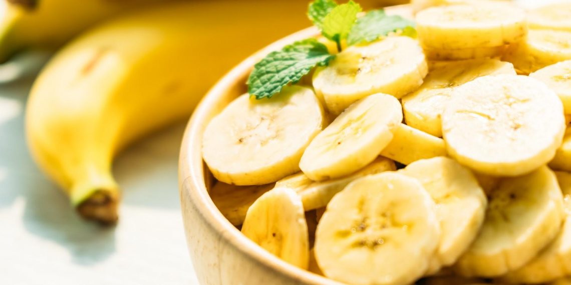 Sliced bananas in a bowl with fresh mint leaves.