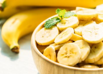 Sliced bananas in a bowl with fresh mint leaves.