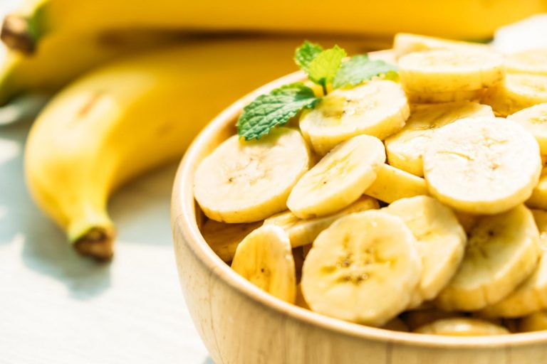 Sliced bananas in a bowl with fresh mint leaves.