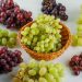 Mixed grapes arranged around a wicker basket on white background.