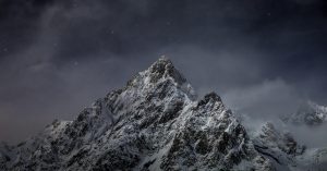 Snow-covered mountain peak under a starry sky.