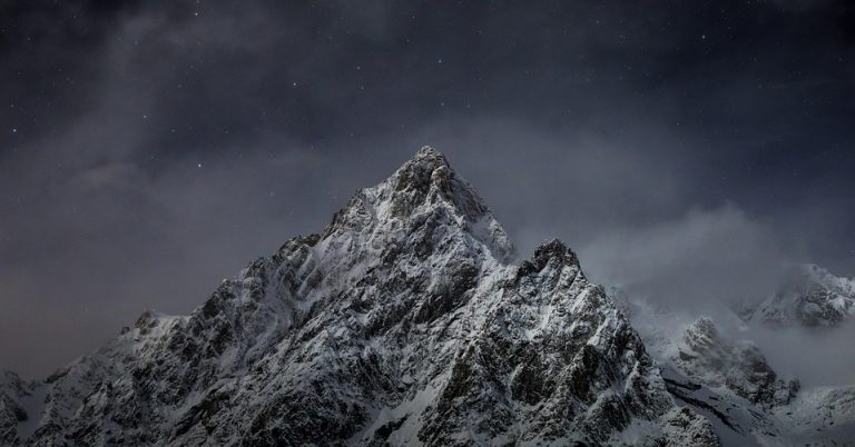 Snow-covered mountain peak under a starry sky.