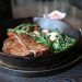 Grilled T-bone steak with vegetables in cast iron skillet.