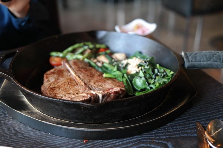 Grilled T-bone steak with vegetables in cast iron skillet.