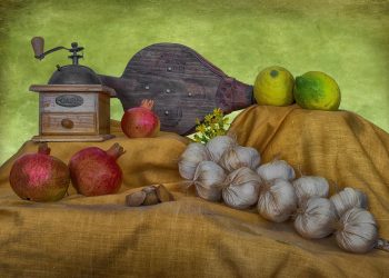 Vintage coffee grinder and fresh produce on a rustic cloth display.