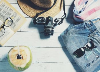 Straw hat and camera with denim shorts for beach vacation.