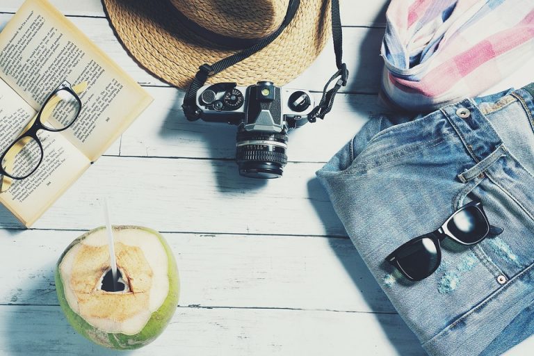 Straw hat and camera with denim shorts for beach vacation.