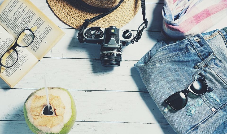 Straw hat and camera with denim shorts for beach vacation.