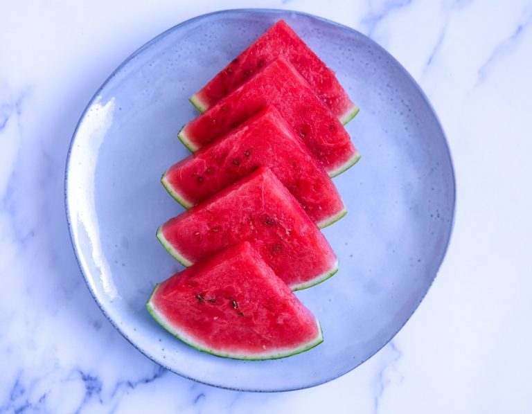 Slices of fresh watermelon arranged on a blue plate.