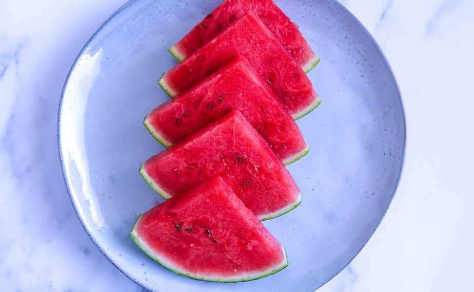 Slices of fresh watermelon arranged on a blue plate.