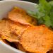 Crispy sweet potato chips garnished with parsley in a white bowl.