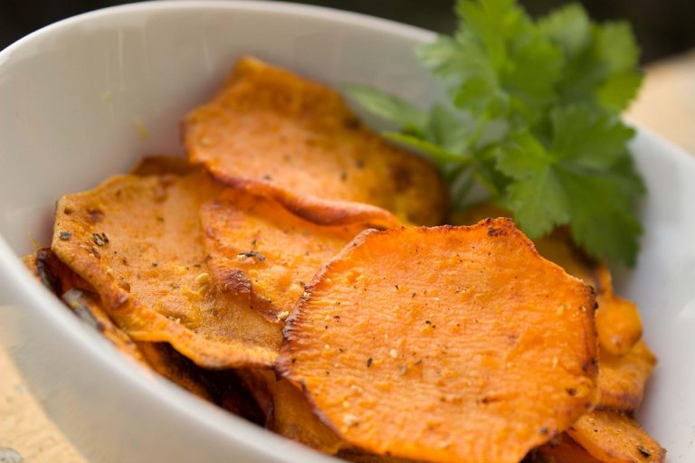 Crispy sweet potato chips garnished with parsley in a white bowl.