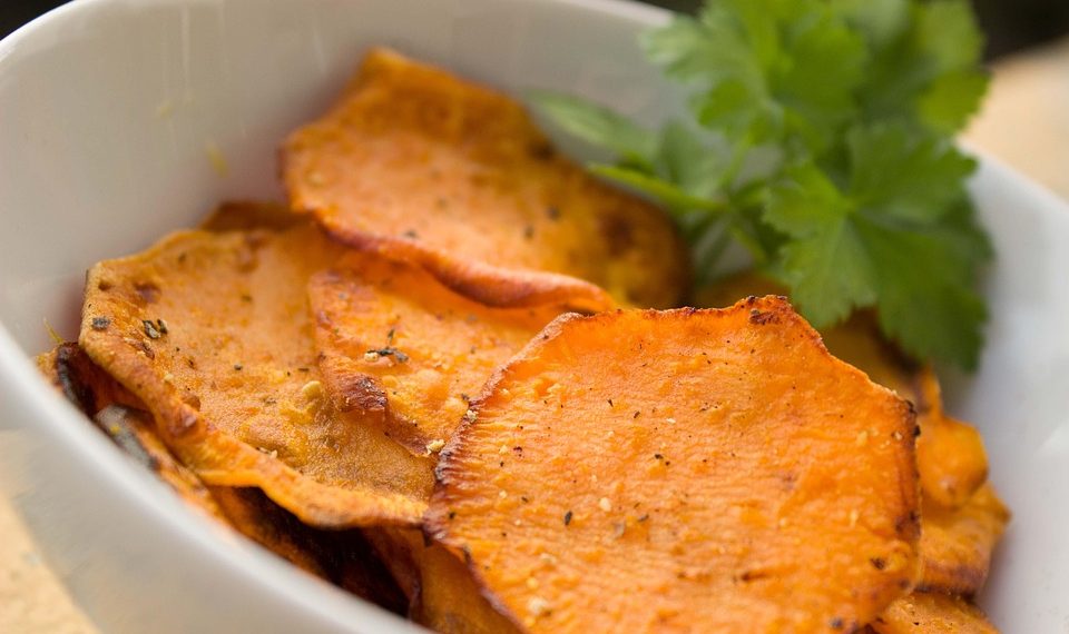 Crispy sweet potato chips garnished with parsley in a white bowl.