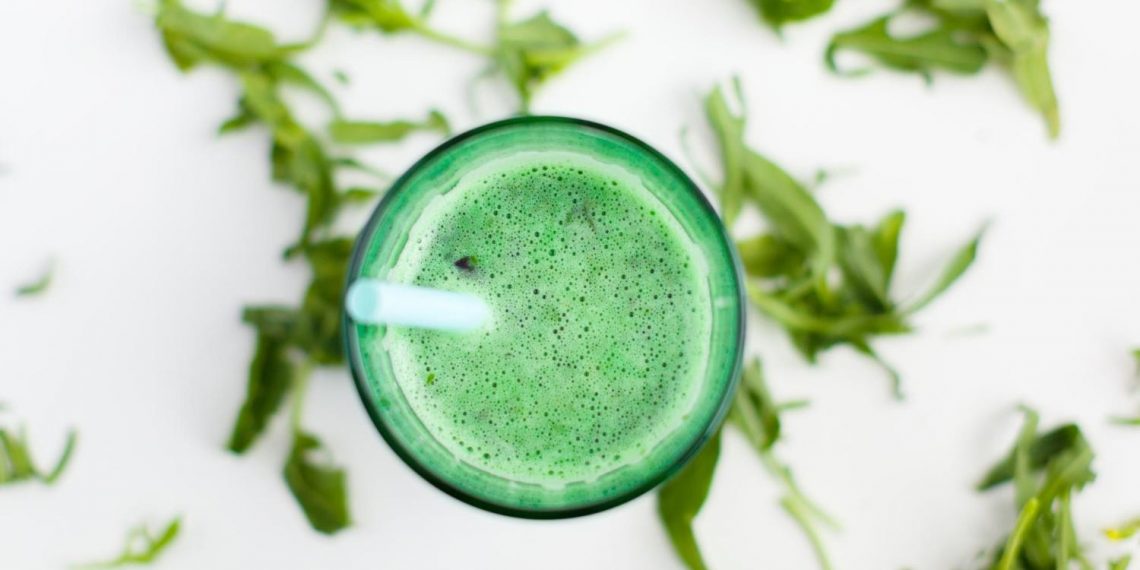 Green smoothie with mint leaves and a blue straw