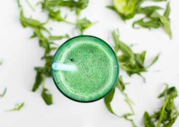 Green smoothie with mint leaves and a blue straw