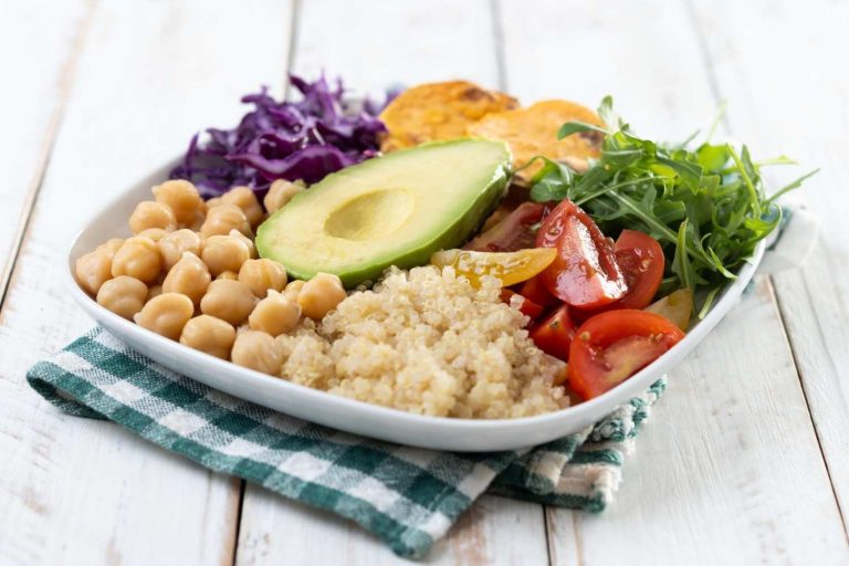 Plate of fresh quinoa salad with avocado, chickpeas, and veggies.