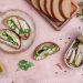 Sardine toasts with jalapeños and parsley on a plate with sliced bread.