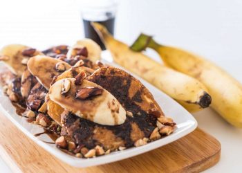 Banana pancakes topped with almonds and chocolate syrup.