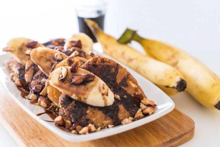 Banana pancakes topped with almonds and chocolate syrup.