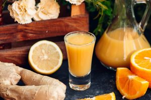 Ginger citrus juice in a glass with fresh lemon and orange slices.