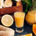 Ginger citrus juice in a glass with fresh lemon and orange slices.