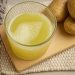 Potato juice in a glass on a wooden board near whole potatoes.