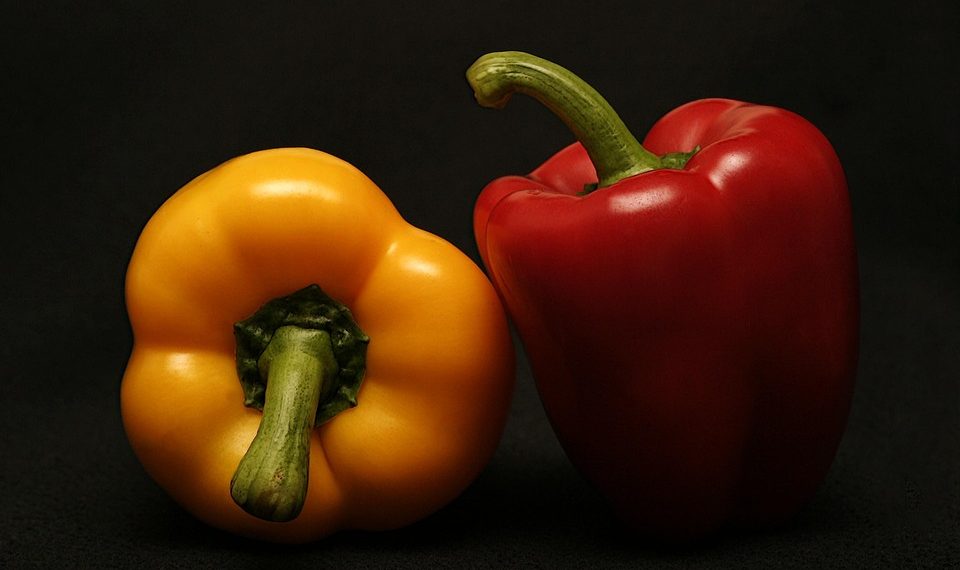 Yellow and red bell peppers on a black background.