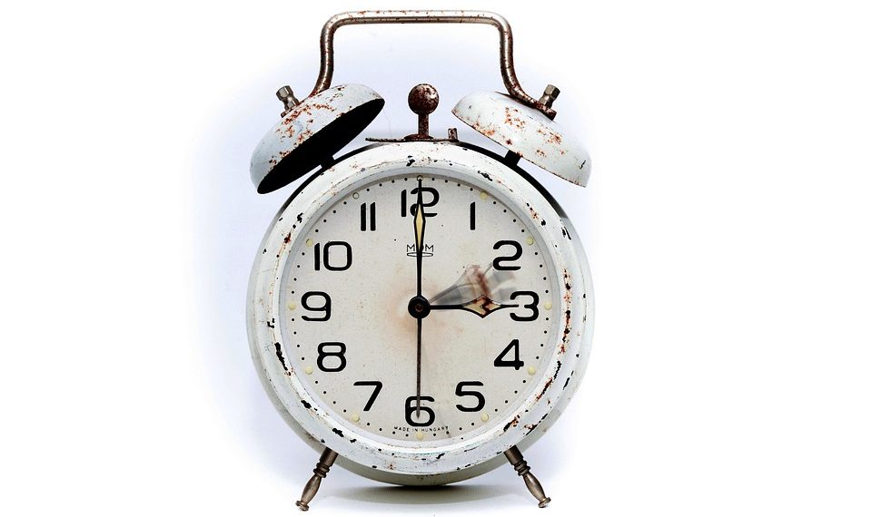 Rustic vintage alarm clock with weathered finish.