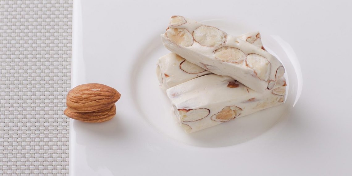 Almond nougat bars on a white plate.