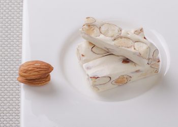 Almond nougat bars on a white plate.