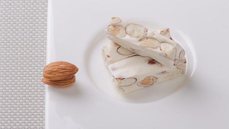 Almond nougat bars on a white plate.