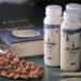 Almonds spilled next to bottles of Ki Nomu almond milk and a book.