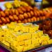 Indian sweets on a tray at a market stall with vibrant colors.