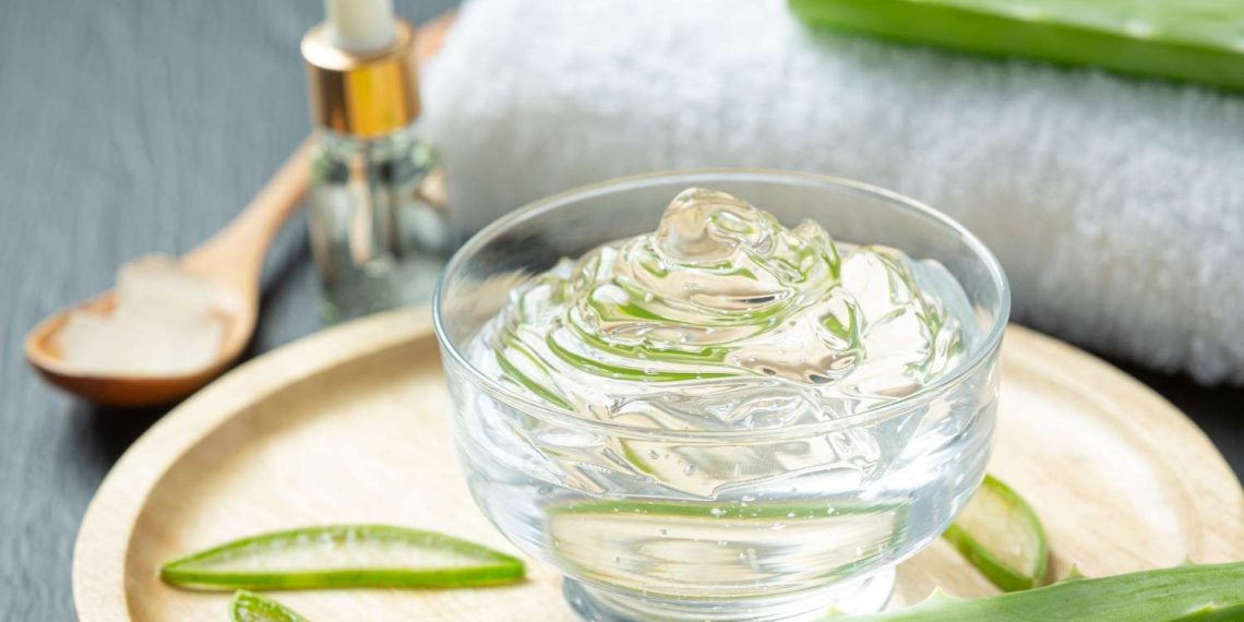 Aloe vera gel in a glass bowl with fresh aloe leaves.