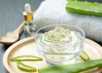 Aloe vera gel in a glass bowl with fresh aloe leaves.